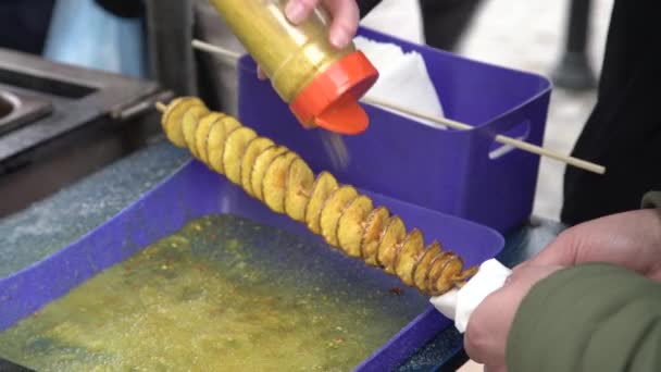 Man Würzt Frittierte Goldene Spiralkartoffeln Auf Einem Holzstab Mit Salz — Stockvideo