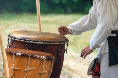 Kırsal giysiler giyen iken açık havada deri davul oynayan adam eller. Geleneksel kabile davul performansı