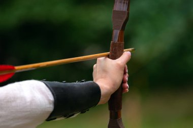 Archer hedefe nişan alarak yay tutuyor. Okçuluk Yarışması, açık hava aktivitesi