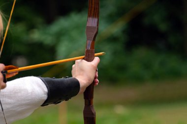 Archer hedefe nişan alarak yay tutuyor. Okçuluk Yarışması, açık hava aktivitesi