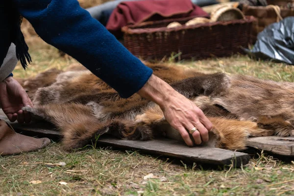 Man hands picking up wild animal fur of the ground. Animal coat skin for sale at rural village