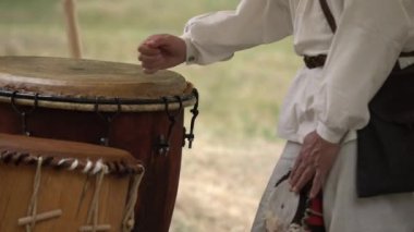 Kırsal giysiler giyen iken açık havada deri davul oynayan adam eller. Geleneksel kabile davul performansı