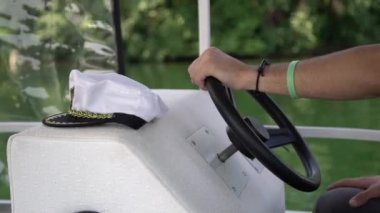 Kaptan, direksiyon simidini el yanında beyaz şapkalı bir teknede tutuyor. Açık sularda Yelkenli ile yaz saati tatil, bir yatta erkek Kaptan şapka
