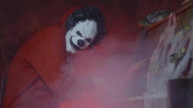 Arka planda mistik sis ve balkabağı ile piyano çalan korkunç palyaço cadılar bayramı maskesi ile tanınmayan adam. Gece korkunç cadılar bayramı parti performansı