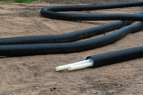 Zwarte PVC elektrische buizen met draden op de grond. Bouwplaats, hoogspanningslijn met kabel draden — Stockfoto