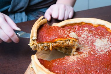 Chicago pizza üst görünümü. Kadın elleri domates sosu ve sığır eti ile Chicago tarzı derin çanak İtalyan peynir pizza kesme içinde karşılamak
