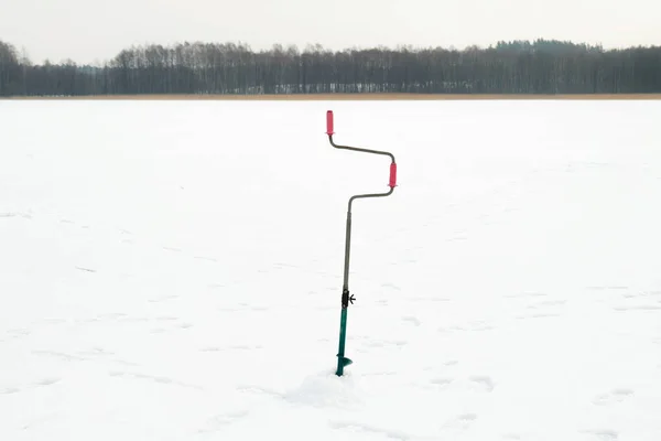 Pesca de invierno en el hielo. Perforando un agujero en el hielo. Relajarse en la naturaleza —  Fotos de Stock