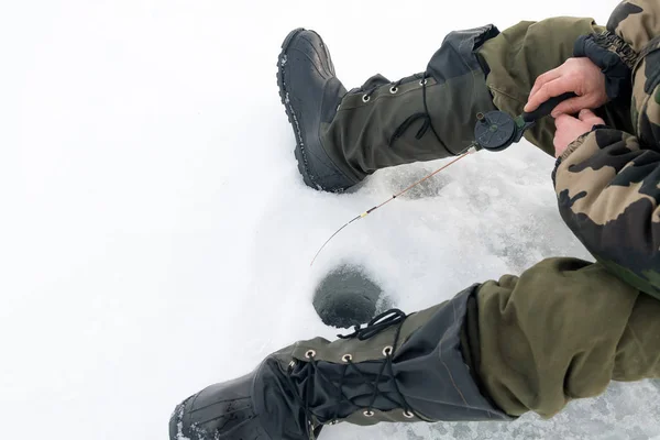 Зимняя рыбалка на льду. Человек, трясущий приманкой в ледяной дыре. Отдых в дикой природе — стоковое фото