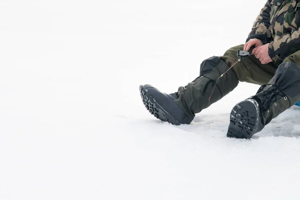 Wintervissen op ijs. Een man die in een ijsgat aan het wiebelen is. Ontspannen in het wild Rechtenvrije Stockfoto's