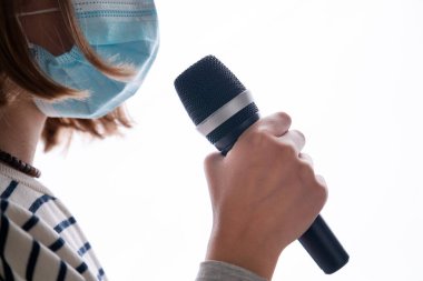 Tıbbi yüz maskesi takan ve beyaz arka planda izole edilmiş mikrofon tutan müzisyenlere yakın çekim. Corona virüsü nedeniyle gösteri ve festival iptal edildi.