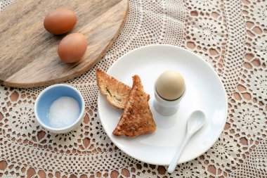 Kahvaltıda kızarmış ekmekle birlikte bir fincanda kaynamış yumurta. Mutfak masasında sağlıklı yemek..