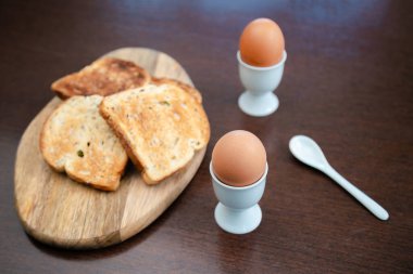 Kahvaltıda kızarmış ekmekle birlikte bir fincanda kaynamış yumurta. Mutfak masasında sağlıklı yemek..