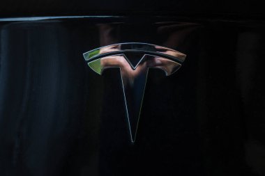 Prague, Czech Republic - June 2020: Tesla motors car badge logo dark background. Modern electric vehicle manufacturer. clipart
