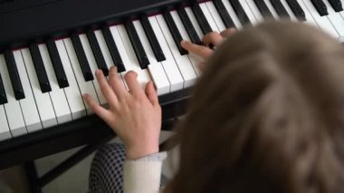 Ev müziği stüdyosunda piyano çalan bir gencin yakın çekimi. Çevrimiçi dersi alan ve modern elektrikli piyano üzerinde pratik yapan bir kız.