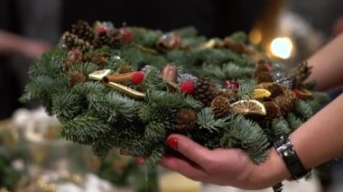Güzel ve renkli el ele tutuşan kişi Noel çelengi, çam kozalakları ve diğer dekorasyonlarla süslenmiş yeşil ladin dalları yaptı. Ellerinde Noel şapkası.
