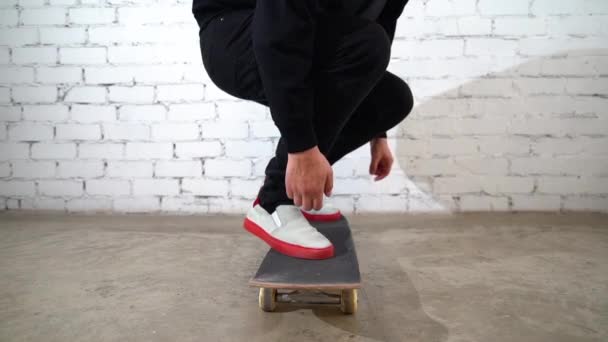 スケートボードのトリックを実行するスケートボーダー 具体的にキックフリップ 選手は白を背景にジャンプ練習を行い 競技の準備をする 極端なスポーツ 若者文化 — ストック動画