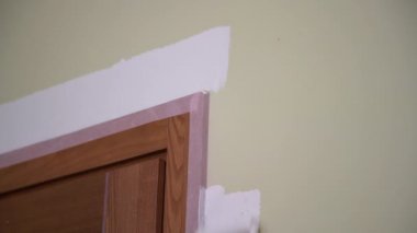 Ellerinizi koruyucu iş eldivenleriyle kapayın kapının etrafındaki duvarları beyaz renklerle boyayın. Boya silindiri kullanın. Ev yenileme projesi. Daire yenileme konsepti.