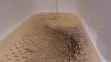 Banyodaki musluktan akan kirli kahverengi su. Paslı eski boru hattı tamiri. Su kirliliği.