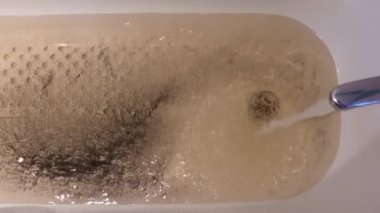 Banyodaki musluktan akan kirli kahverengi su. Paslı eski boru hattı tamiri. Su kirliliği.