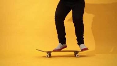 Kaykaycı kaykay numarası yapıyor. Stüdyoda tekme atma numarası yapıyor. Sarı arka planda atlama antrenmanı yapan sporcu, yarışmaya hazırlanıyor. Aşırı spor, gençlik kültürü