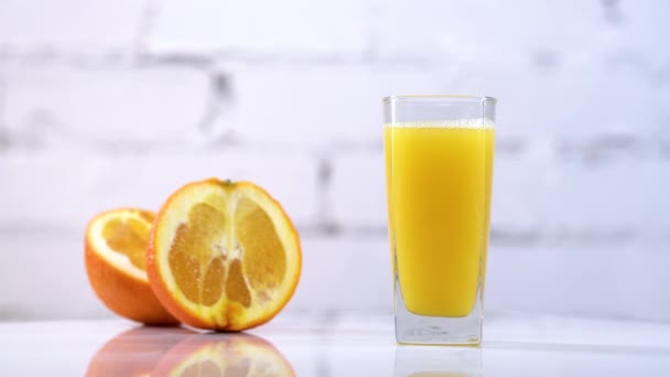 Frisch gepresster Orangensaft in einem Glas auf einem Tisch, daneben Orangenscheiben. Erfrischendes gelbes Getränk mit Früchten auf weißem Hintergrund