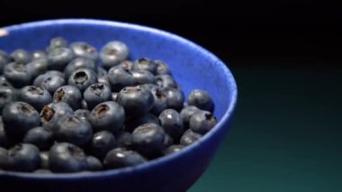 Mavi arka planda yabanmersini dolu seramik kâse. Olgun yabanmersini tabağı. Organik ve sağlıklı yiyecekler..