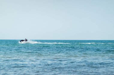 İnsanlar güneşli bir günde mavi denizde su jet ski 'sinin keyfini çıkarıyorlar. Tropik tatil su aktiviteleri.