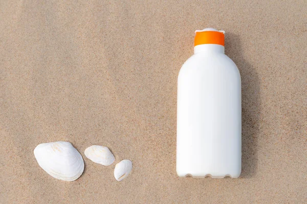 Kumsalda güneşli bir günde kumda güneş kremi. Güneş yanığından korunan beyaz güneş kremi şişesi. Kimse..