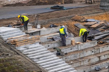 İnşaat temelinde çalışan inşaatçılar. Tepenin yamacındaki beton yapıyı güçlendirir.