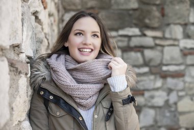 Eski bir taş duvara yaslanmış, gülüyor kız