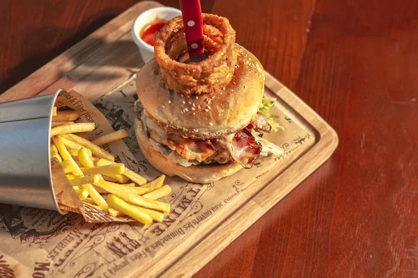 Pastırmalı hamburger ve masada patates kızartması.