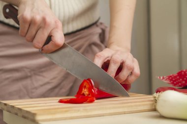 Profesyonel şef taze kırmızı biber dilimliyor. Mutfakta bambu doğrama tahtasıyla, yakın plan, insan yok.