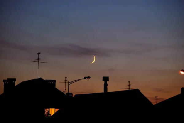 Moon over roof silhouettes