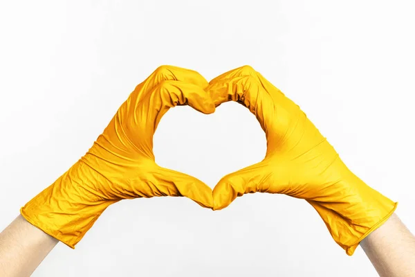Hands in gold latex rubber gloves show heart on a white background