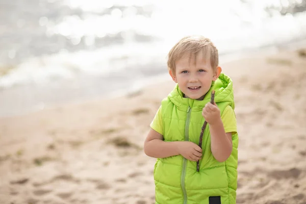 Blonďatý Chlapec Pláži Pozadí Moře Písku Kusem Dřeva Ruce Představa — Stock fotografie