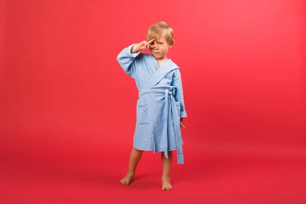Dítě Blonďatý Chlapec Modrém Županu Červeném Jasném Pozadí Ukazuje Znamení — Stock fotografie