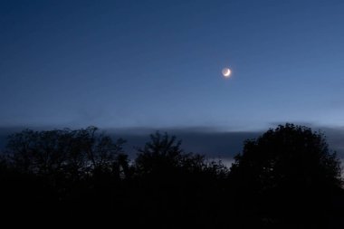 Köyün üstündeki koyu mavi gökyüzündeki ay. Güzel gece manzarası.