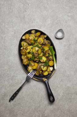 Şükran günü yemeği. Kızarmış patates mantar ve soğan demir tava, cherry domates, sarı peçete, yeşil soğan ve tuz gri arka plan, çatal