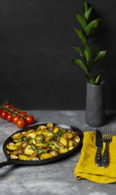 Rus tazelik kızarmış patates mantar ve soğan demir tavada çatal, mantar, domates, gri arka plan, çiçekli vazo