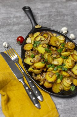 Şükran günü yemeği. Geleneksel tazelik kızarmış patates mantar ve soğan demir tavada çatal ve bıçak, taze mantar ve gri arka plan, kiraz domates