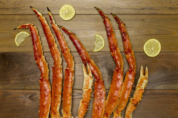 Luxury food. Crab claws with lemon slices on brown wooden background