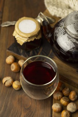 Çay kavanoz ve örme battaniye yakınındaki, fındık, tahta arka plan ile kaşık ile cam Kupası Çaydanlık, reçel.