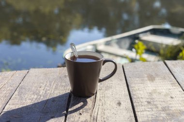Çay kaşık ahşap arka plan, nehir ve tekne arkasında ile