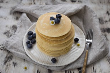 Yaban mersini beyaz tabak ve çatal, beyaz tahta arka plan ile gri peçete ile Pancakes 