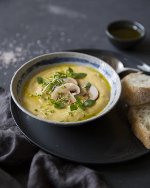 Mantar, otlar ve gri plaka siyah arka plan üzerine beyaz ekmek ile krem peynir çorbası