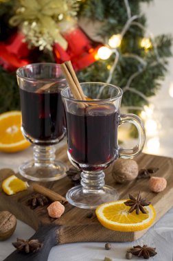 Kış kompozisyon. Gözlüklü beyaz arka plan, ahşap tahta üzerinde mulled şarap. Köknar çelenk, çan, tinsel ve çelenk, portakal, tarçın ve baharat yakınındaki.