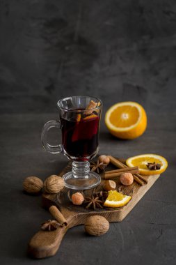 Kış Noel kompozisyon. Gözlük siyah arka plan, kırmızı mulled şarap. Köknar çelenk, portakal, tarçın, fındık, koni ve baharat yakınındaki.