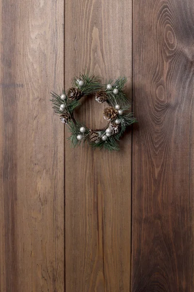 Christmas small green wreath with cones at wood board. Copy space, template. Festive theme
