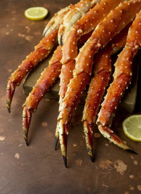 Taze lezzetli Kamçatka yengecin pençe kahverengi zemin ahşap tahtaya limon dilimleri ile Kral