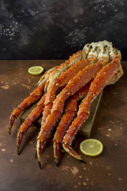 Taze lezzetli Kamçatka yengecin pençe kahverengi zemin ahşap tahtaya limon dilimleri ile Kral